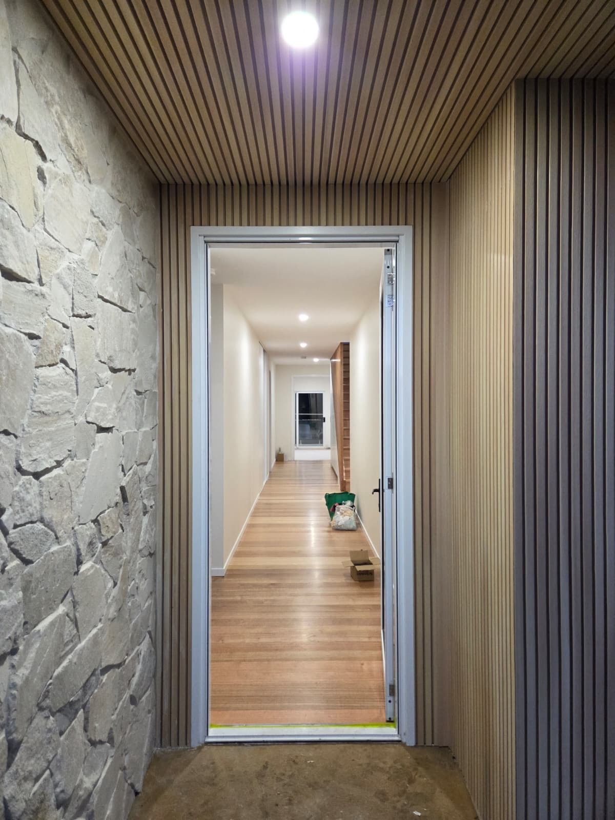 Entry soffit downlight in timber batten and stone entry, wired by MVS Connect