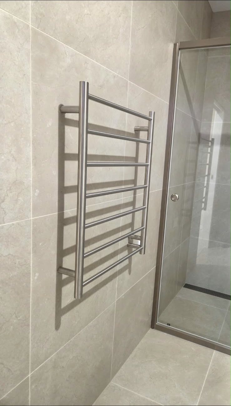 Hard-wired heated towel rail installed by MVS Connect in a tiled bathroom